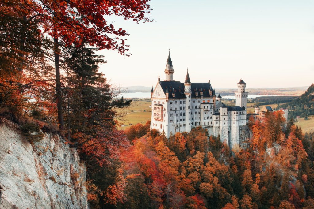 Autumn trees on the hill reveal a view on charming Neuschwanstein Castle